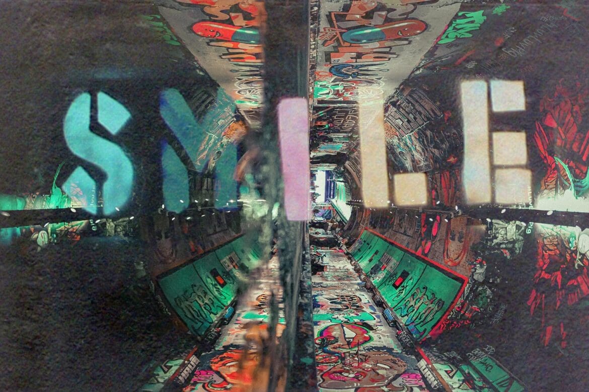 Banksy-inspired graffiti artwork with the word "SMILE" overlaid in a vibrant urban tunnel