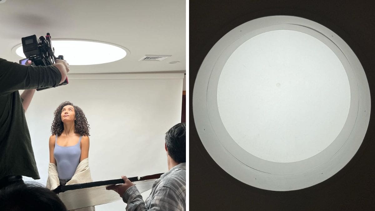 Creative director overseeing a studio shoot with a model under a circular skylight, guiding lighting and framing decisions.