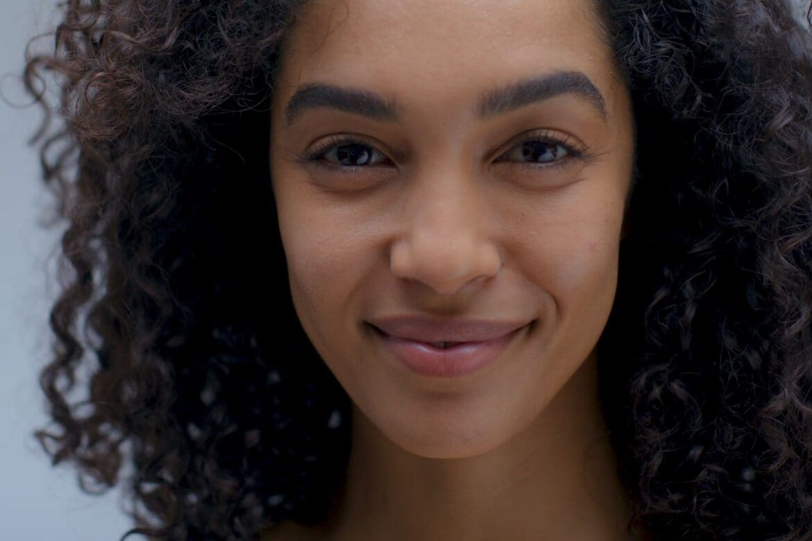 Close-up of a woman with curly hair and radiant skin, representing the beauty and wellness focus of Nutrafol x Sephora Skin campaign.