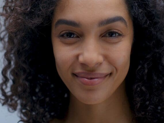Close-up of a woman with curly hair and radiant skin, representing the beauty and wellness focus of Nutrafol x Sephora Skin campaign.