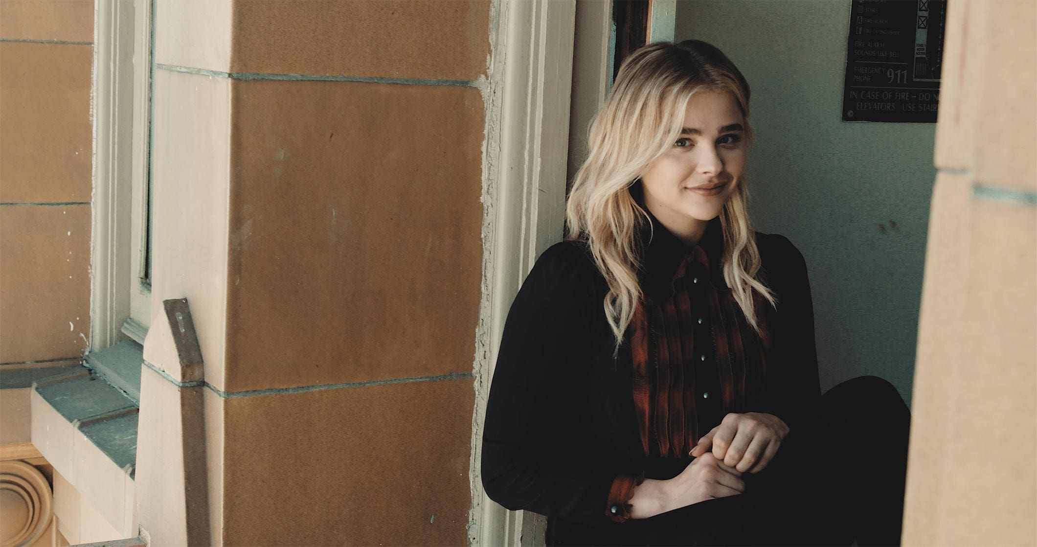 Chloë Grace Moretz smiling in a behind-the-scenes moment during the filming of the Coach fragrance campaign.