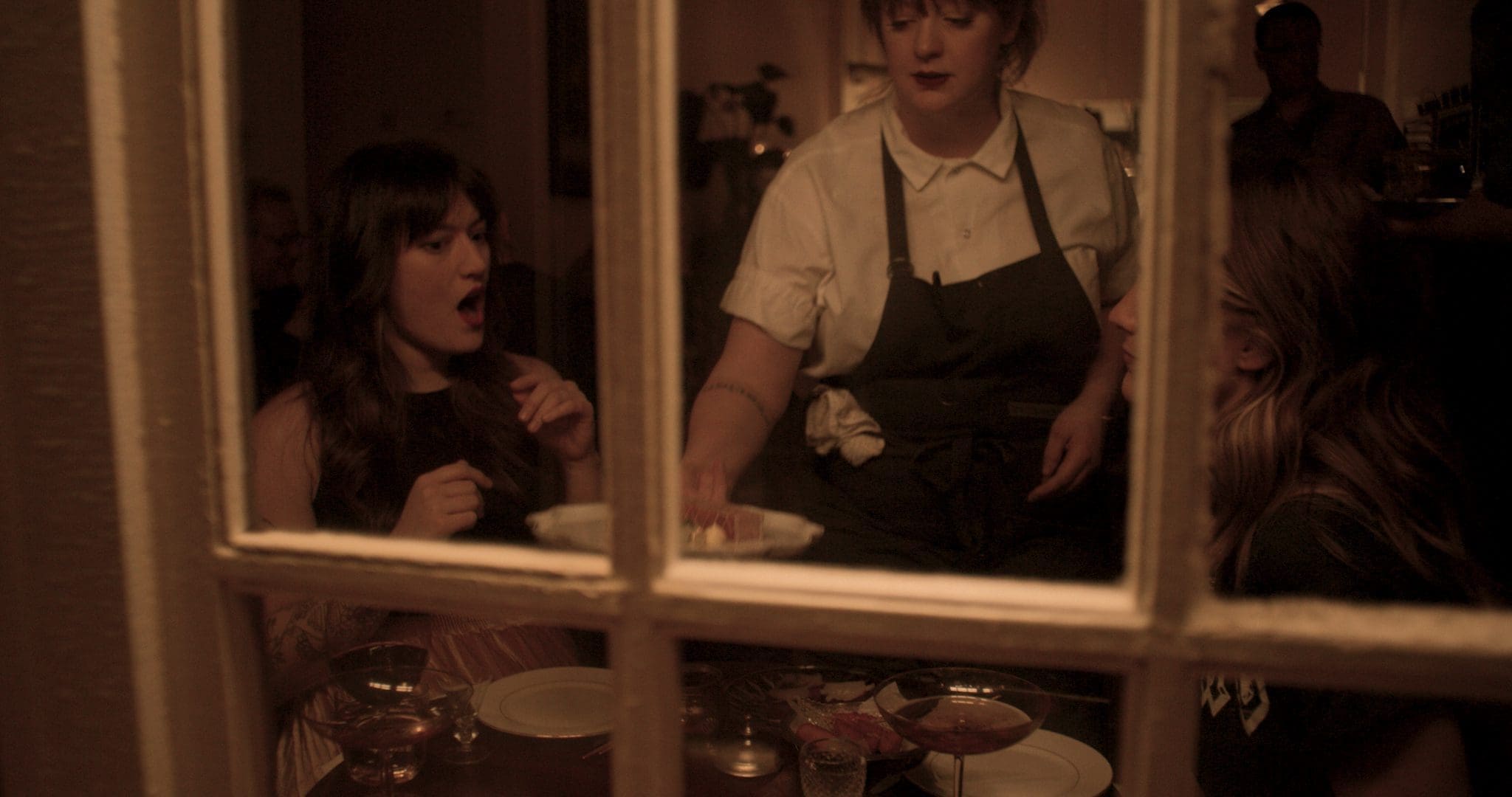 RIOT, NYC Creative Agency: Chef Jamie Malone serves food to guests at Grand Cafe, captured through a window, highlighting the intimate and welcoming atmosphere of the restaurant. Chef Jamie Malone serves food to guests at Grand Cafe, captured through a window, highlighting the intimate and welcoming atmosphere of the restaurant.