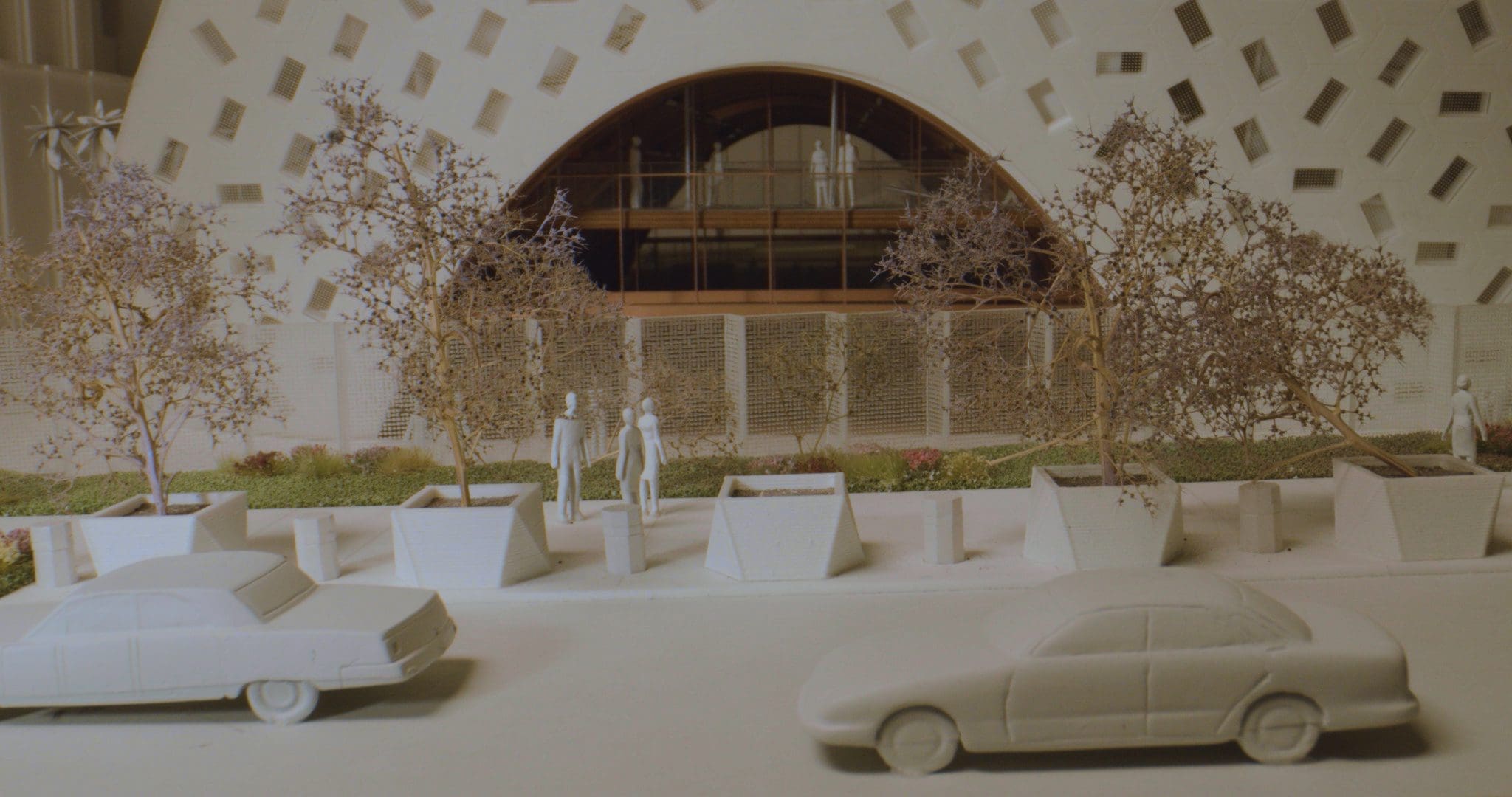 RIOT, NYC Creative Agency: A detailed architectural model by Shohei Shigematsu showing miniature cars, trees, and figures in front of a building design. A detailed architectural model by Shohei Shigematsu showing miniature cars, trees, and figures in front of a building design.