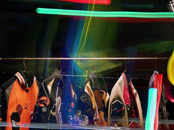 Coach Varsity jackets from the Women’s Fall 2016 collection displayed on a rack with neon graffiti-inspired lighting effects.
