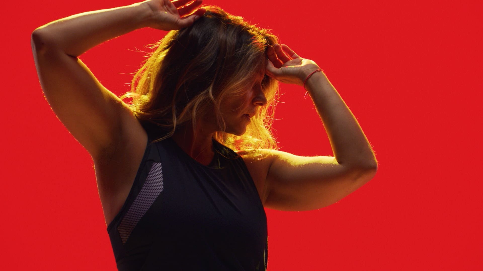 RIOT, NYC Creative Agency: Laurie Cole posing against a bold red background, embodying strength and energy, from the SoulCycle docufilm series. Laurie Cole posing against a bold red background, embodying strength and energy, from the SoulCycle docufilm series.