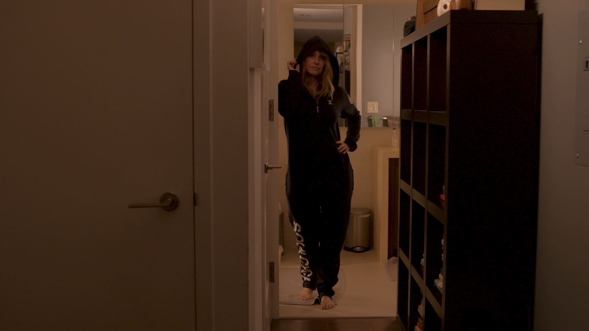 RIOT, NYC Creative Agency: Laurie Cole standing confidently in a dimly lit hallway, wearing a SoulCycle hoodie, embodying calm strength and introspection in this docufilm still. Laurie Cole standing confidently in a dimly lit hallway, wearing a SoulCycle hoodie, embodying calm strength and introspection in this docufilm still.