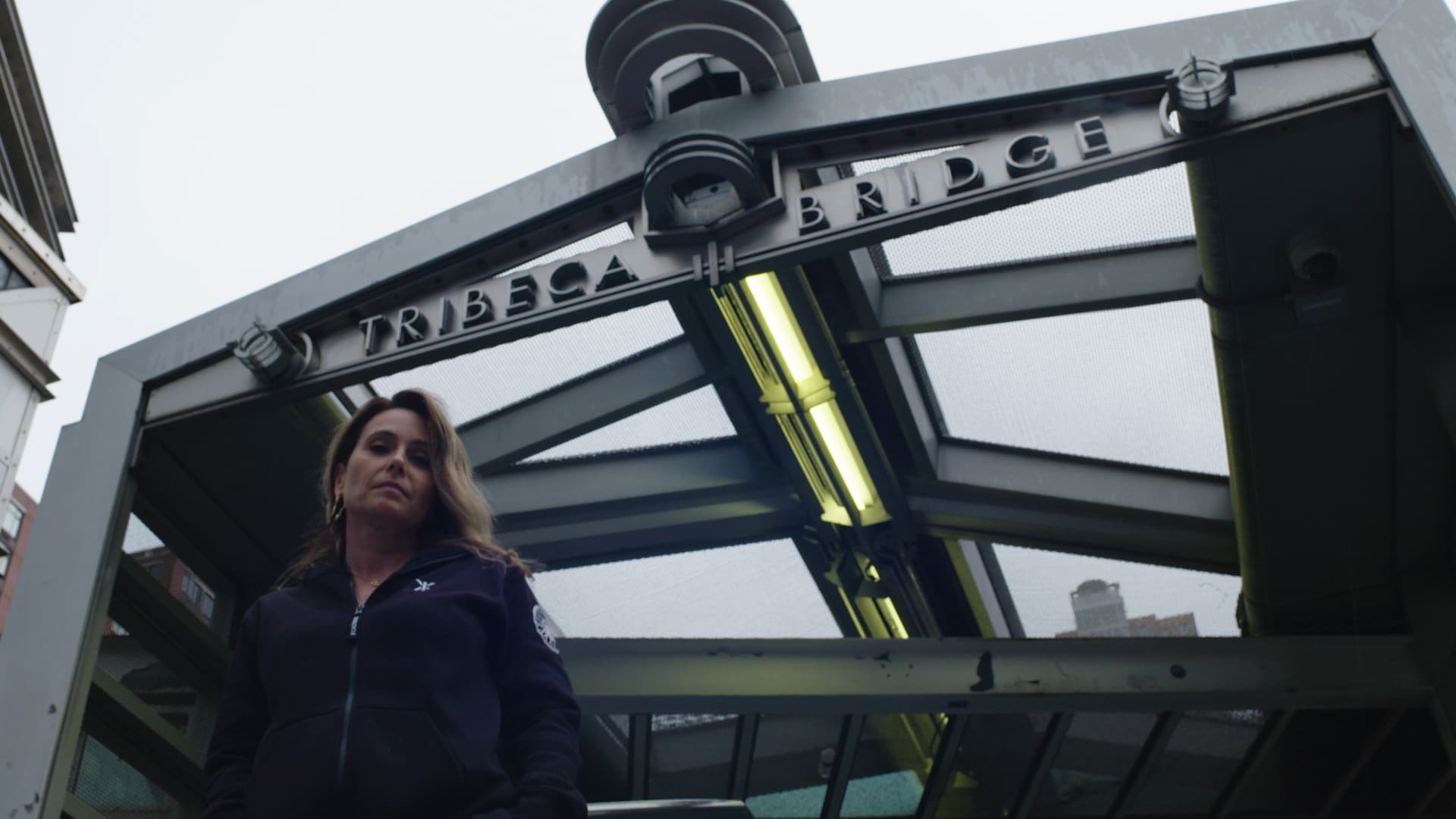RIOT, NYC Creative Agency: Laurie Cole standing confidently beneath the Tribeca Bridge, showcasing her strength and connection to the city in this SoulCycle docufilm still. Laurie Cole standing confidently beneath the Tribeca Bridge, showcasing her strength and connection to the city in this SoulCycle docufilm still.