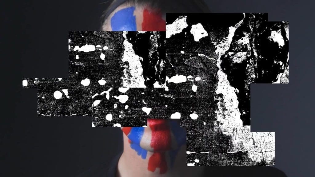 Gareth Pugh with his face painted in Union Jack colors, showcasing a punk-inspired design as part of his collaboration with Sunglass Hut.