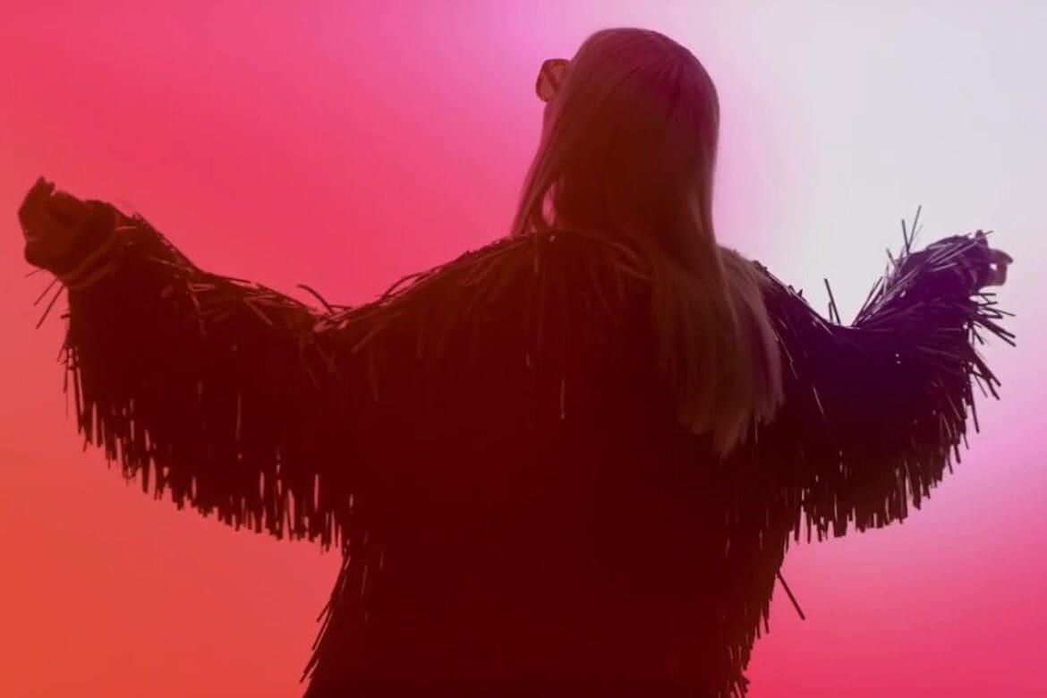 Cailin Russo in a dramatic pose, surrounded by fiery red hues, representing the energetic and powerful Fire Trend for Sunglass Hut’s campaign.