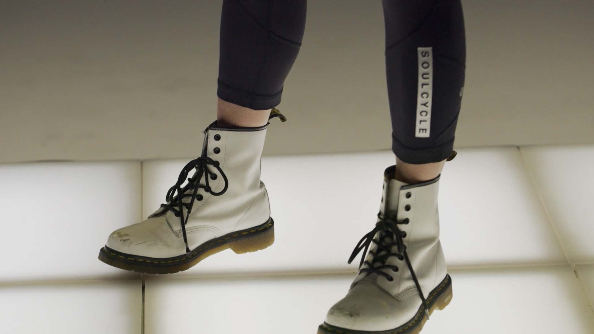 lose-up of Melanie’s white boots paired with SoulCycle-branded leggings, symbolizing her distinctive style and dedication.