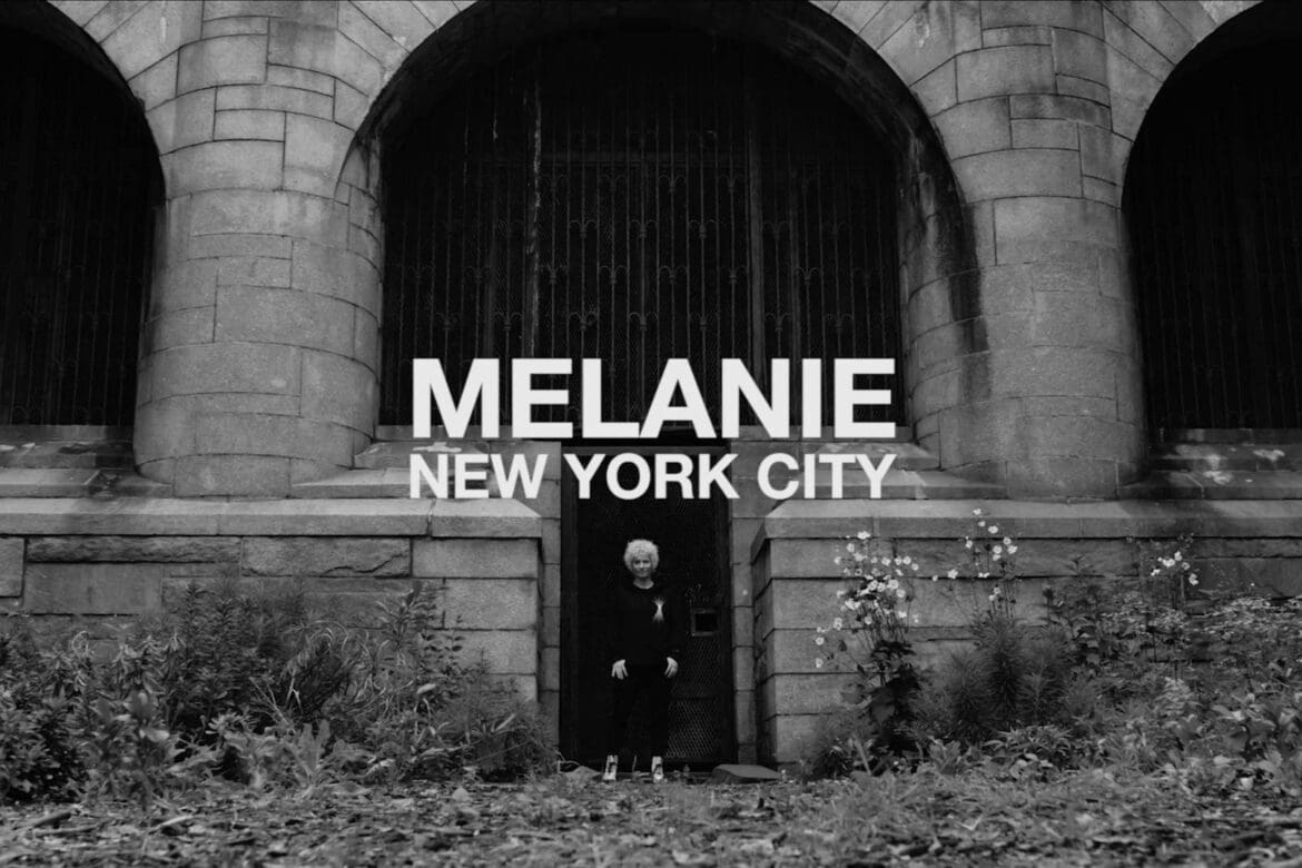 Melanie standing in front of a gothic stone building in New York City, representing her roots and strength as a SoulCycle instructor.