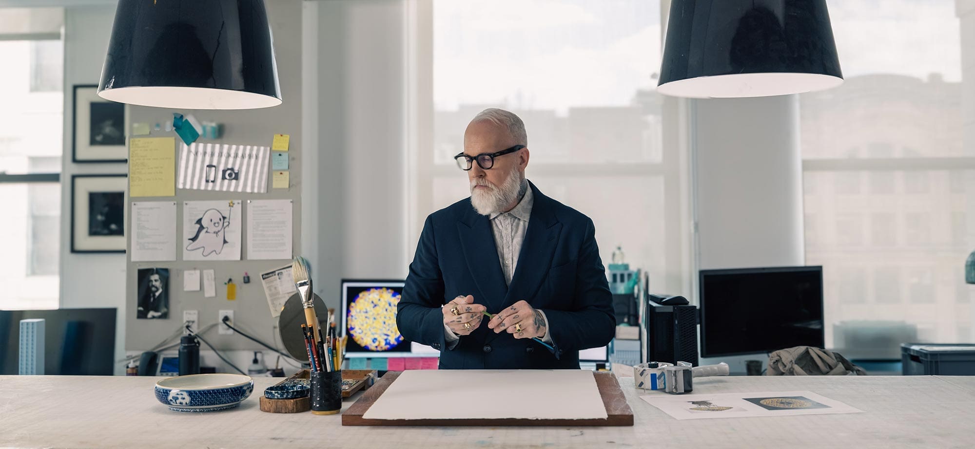 Christopher Young standing over a blank page, surrounded by brushes and creative tools