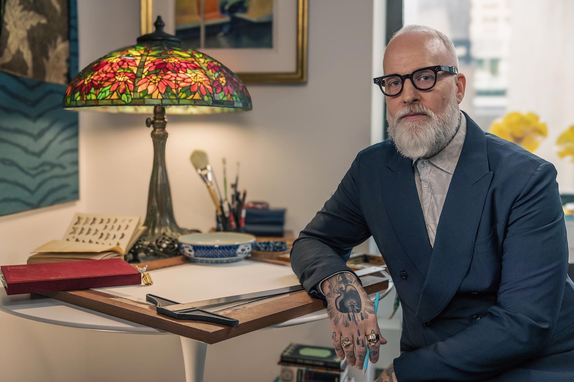 RIOT, NYC Creative Agency: Christopher Young, Tiffany's Vice President Creative Director, seated beside his Tiffany-style lamp and art tools Christopher Young, Tiffany's Vice President Creative Director, seated beside his Tiffany-style lamp and art tools