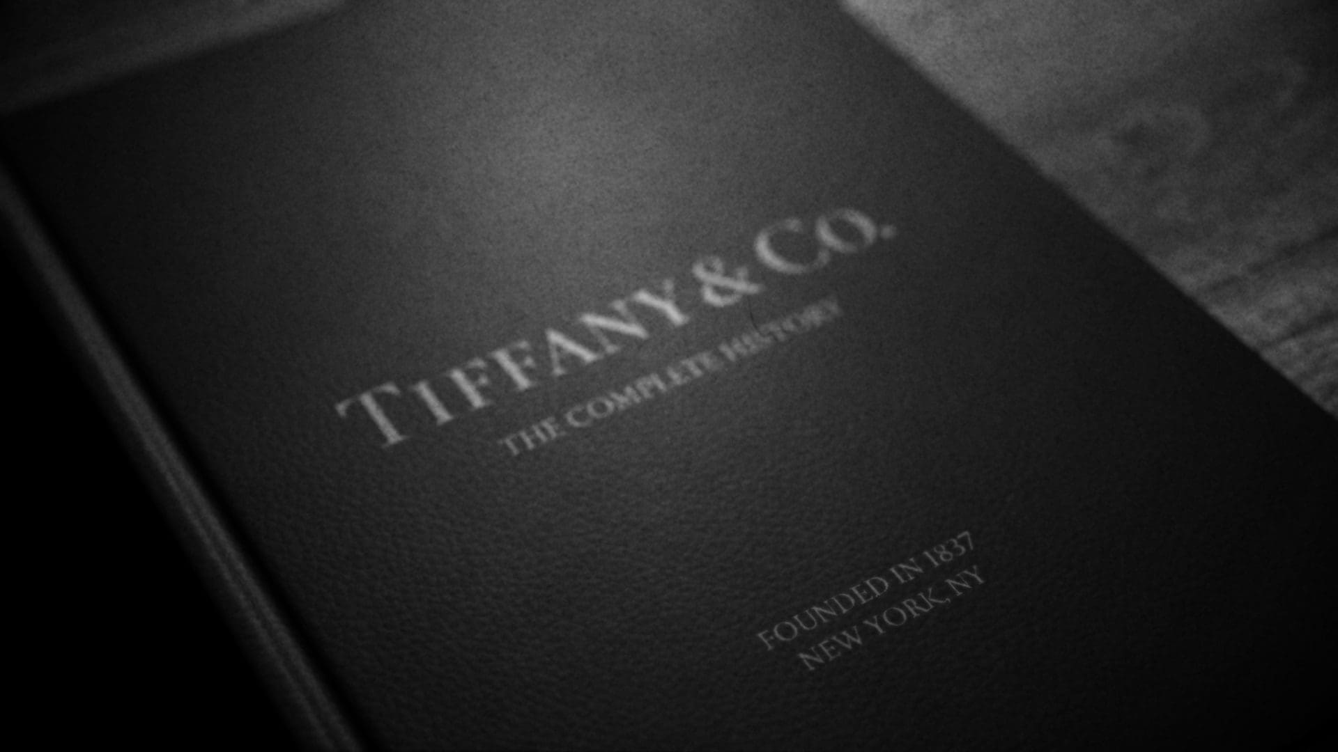 RIOT, NYC Creative Agency: Close-up of a Tiffany & Co. book cover with the title 'The Complete History,' highlighting the founding year 1837 and location New York, NY. Close-up of a Tiffany & Co. book cover with the title 'The Complete History,' highlighting the founding year 1837 and location New York, NY.