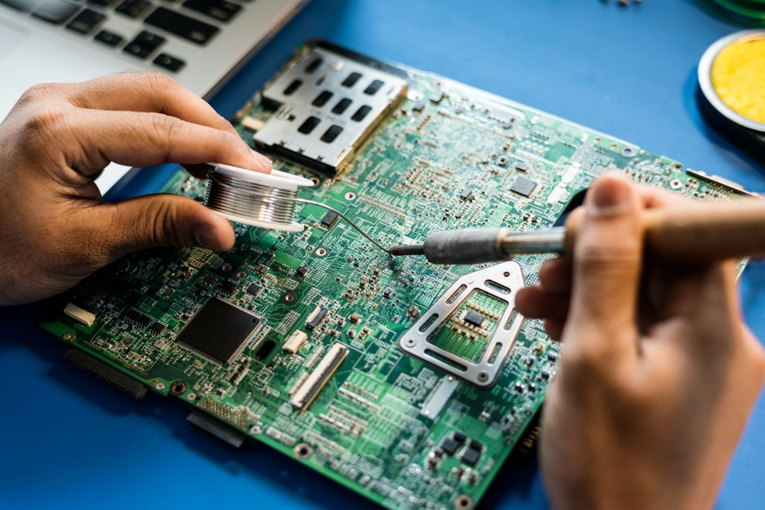 Hands soldering a circuit board to repair an electronic device