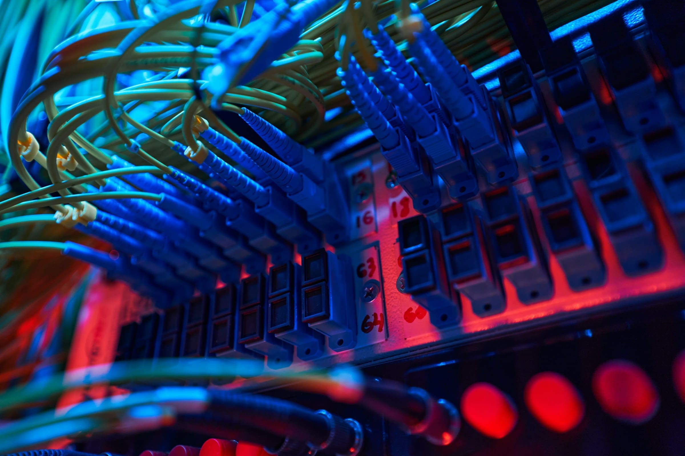 RIOT, NYC Creative Agency: Close-up of glowing fiber optic cables and ports inside a server rack Close-up of glowing fiber optic cables and ports inside a server rack