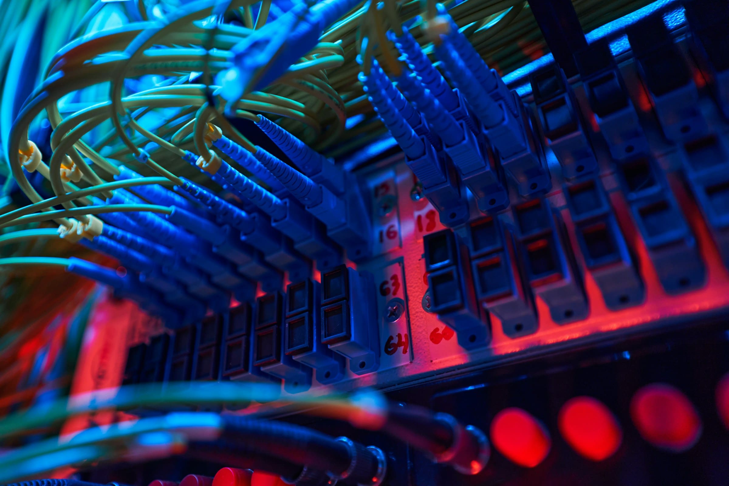 Close-up of glowing fiber optic cables and ports inside a server rack