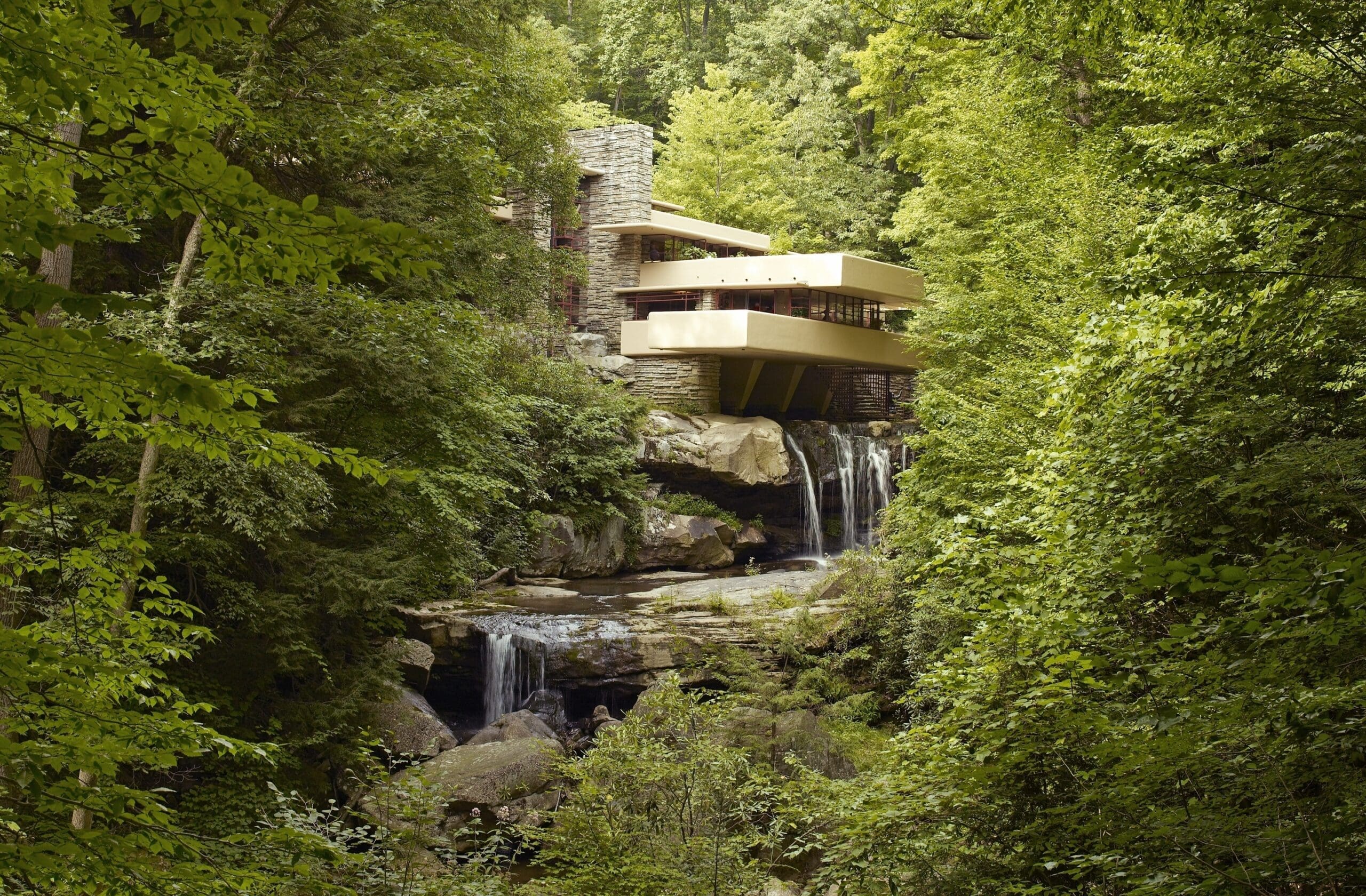 Fallingwater, a house designed by Frank Lloyd Wright, built over a waterfall and surrounded by lush green forest, as seen in 2007.