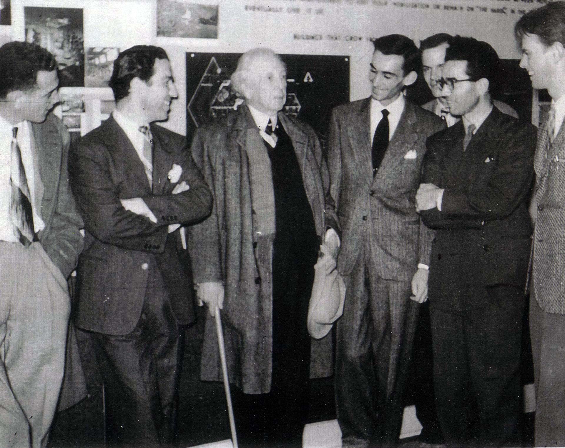 Frank Lloyd Wright with a group of architecture students at the DU School of Architecture, engaging in conversation and sharing ideas.