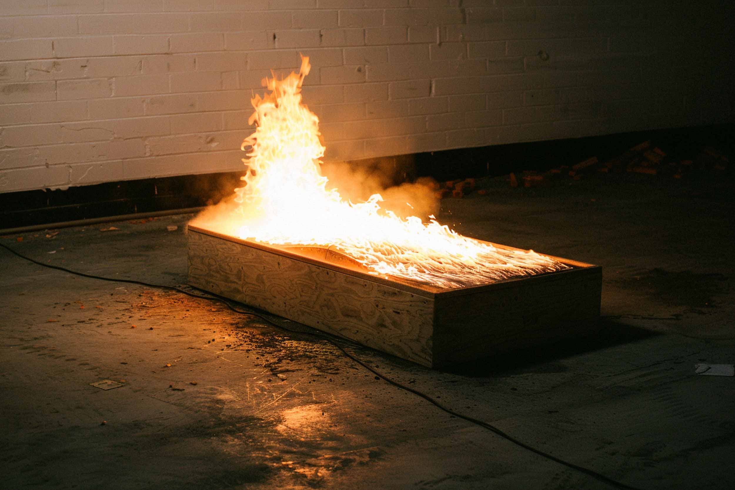 A wooden box engulfed in flames in a dimly lit room — symbolizing the destruction and rebirth of creativity.