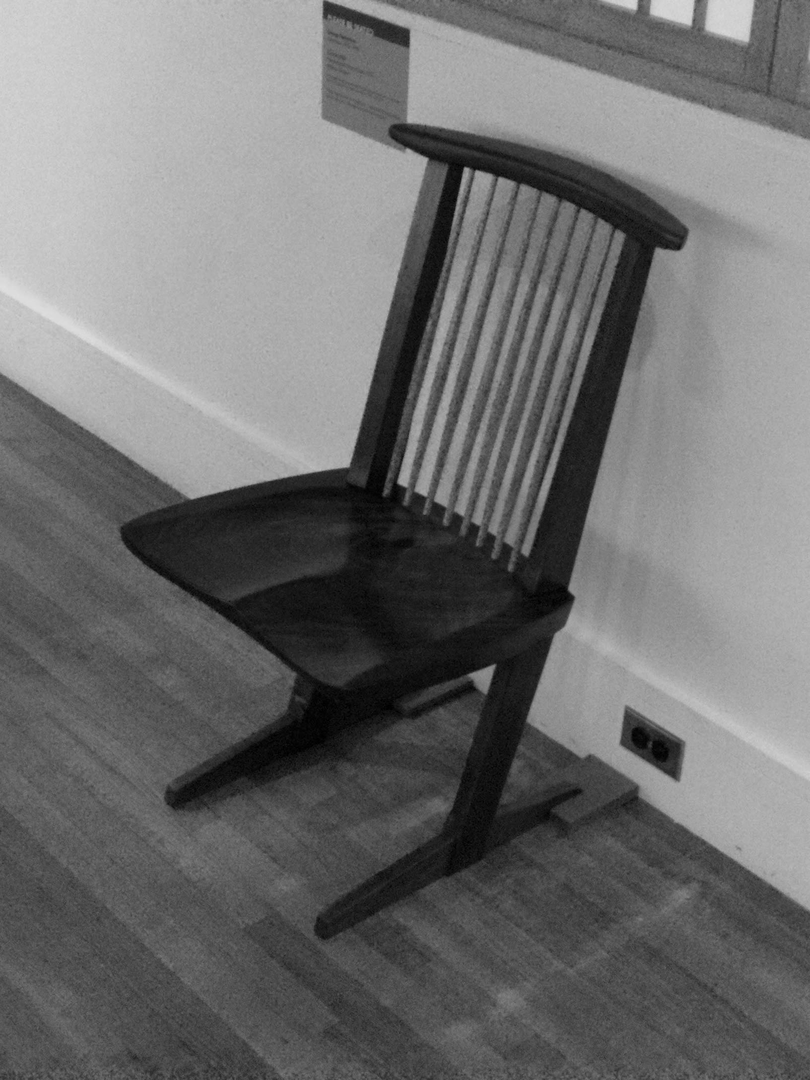 A wooden chair designed by George Nakashima, known for its simple, handcrafted design, showcasing natural wood grain and clean lines.