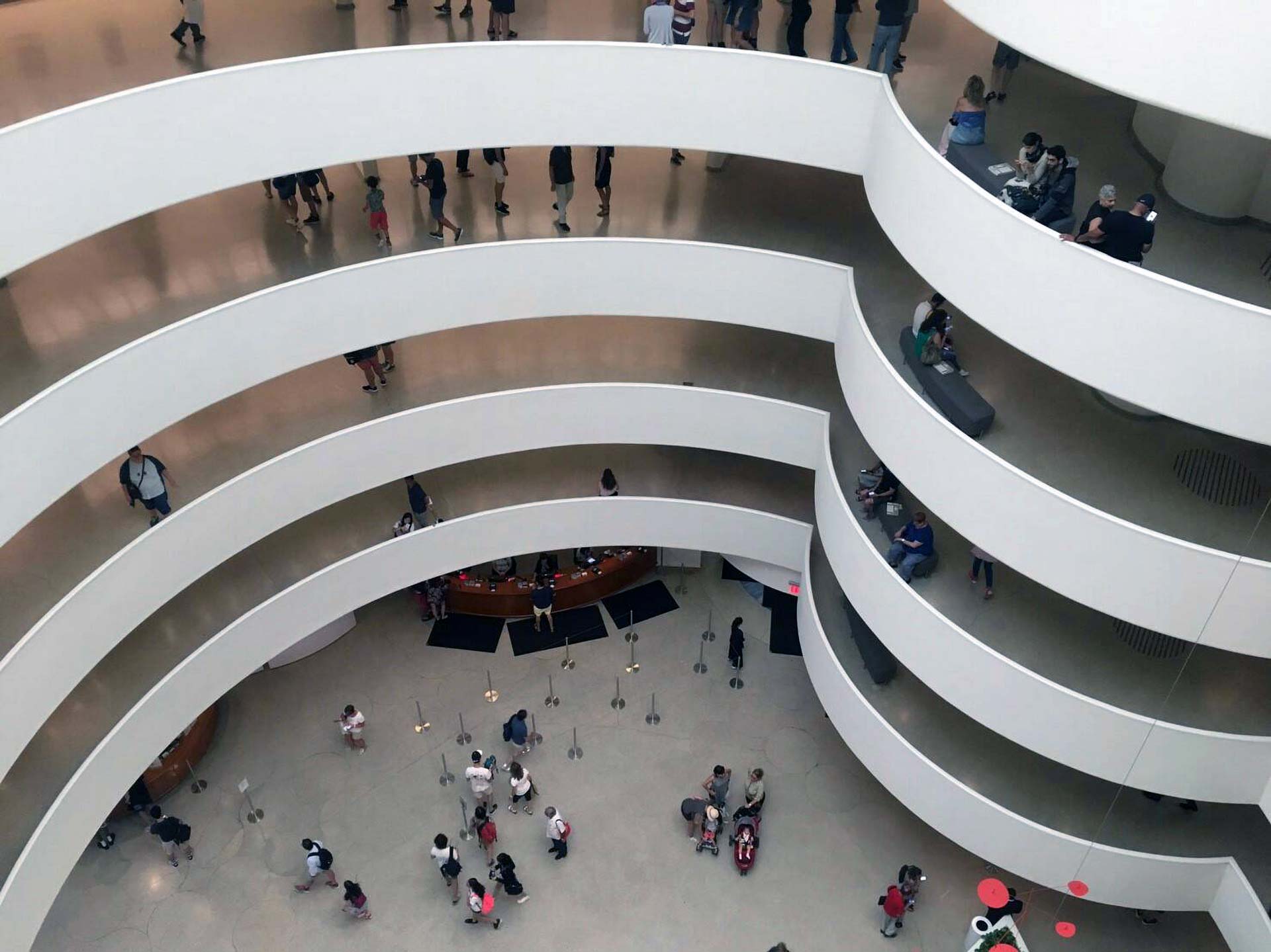 The interior of the Solomon R. Guggenheim Museum, showcasing the iconic spiraling ramps with visitors walking through the exhibits.
