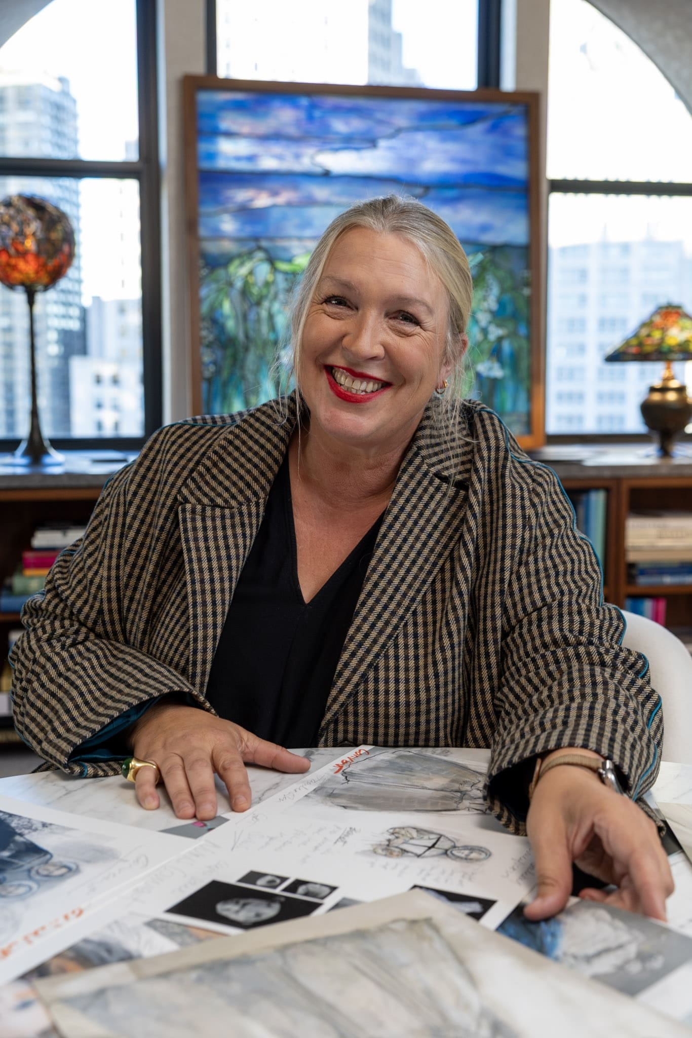 Kate Hawley smiling with costume sketches and design references on table