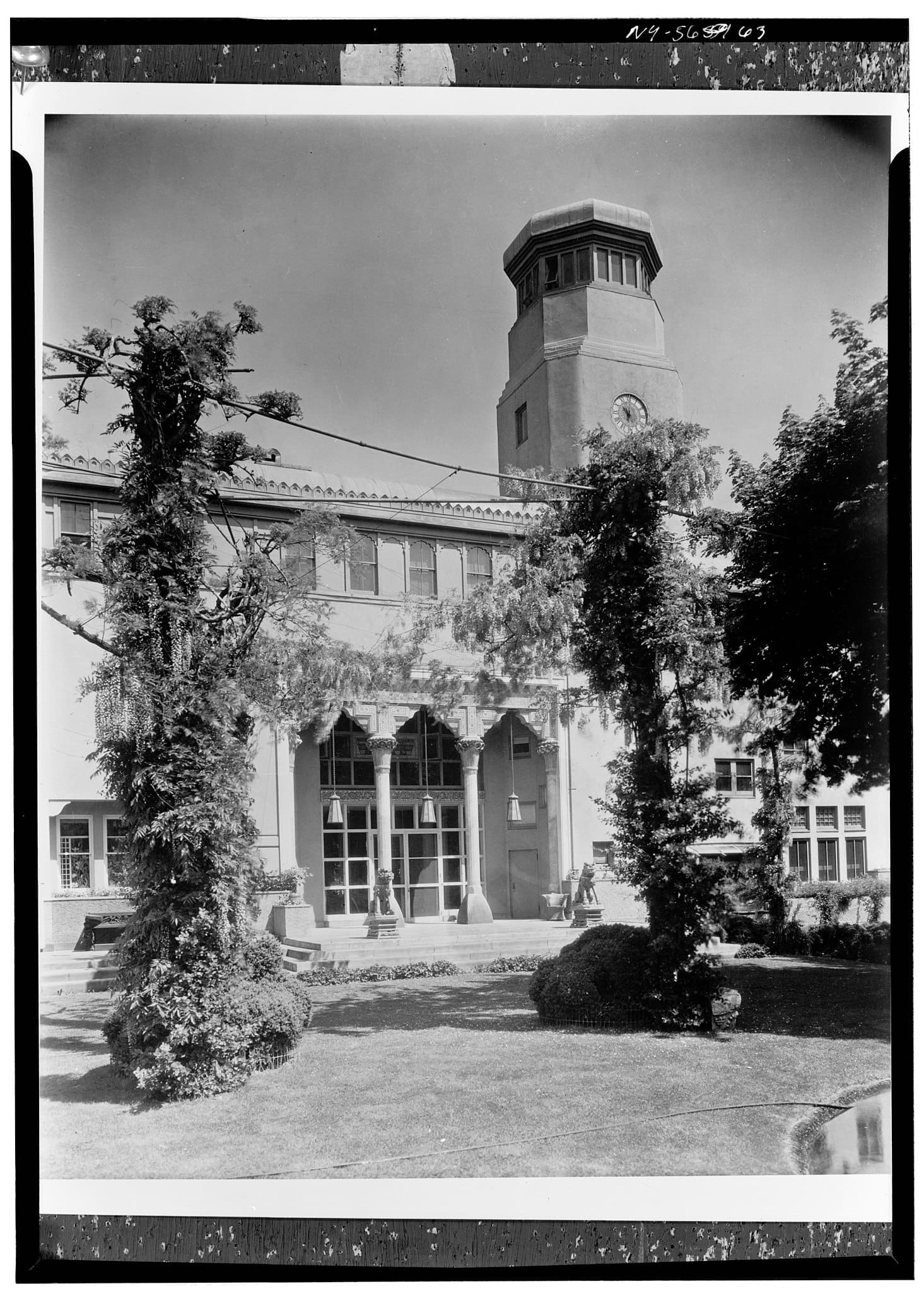 Exterior of Laurelton Hall, showcasing Louis Comfort Tiffany’s architectural masterpiece with its grand columns, clock tower, and intricate details. Photo via Wikimedia Commons.