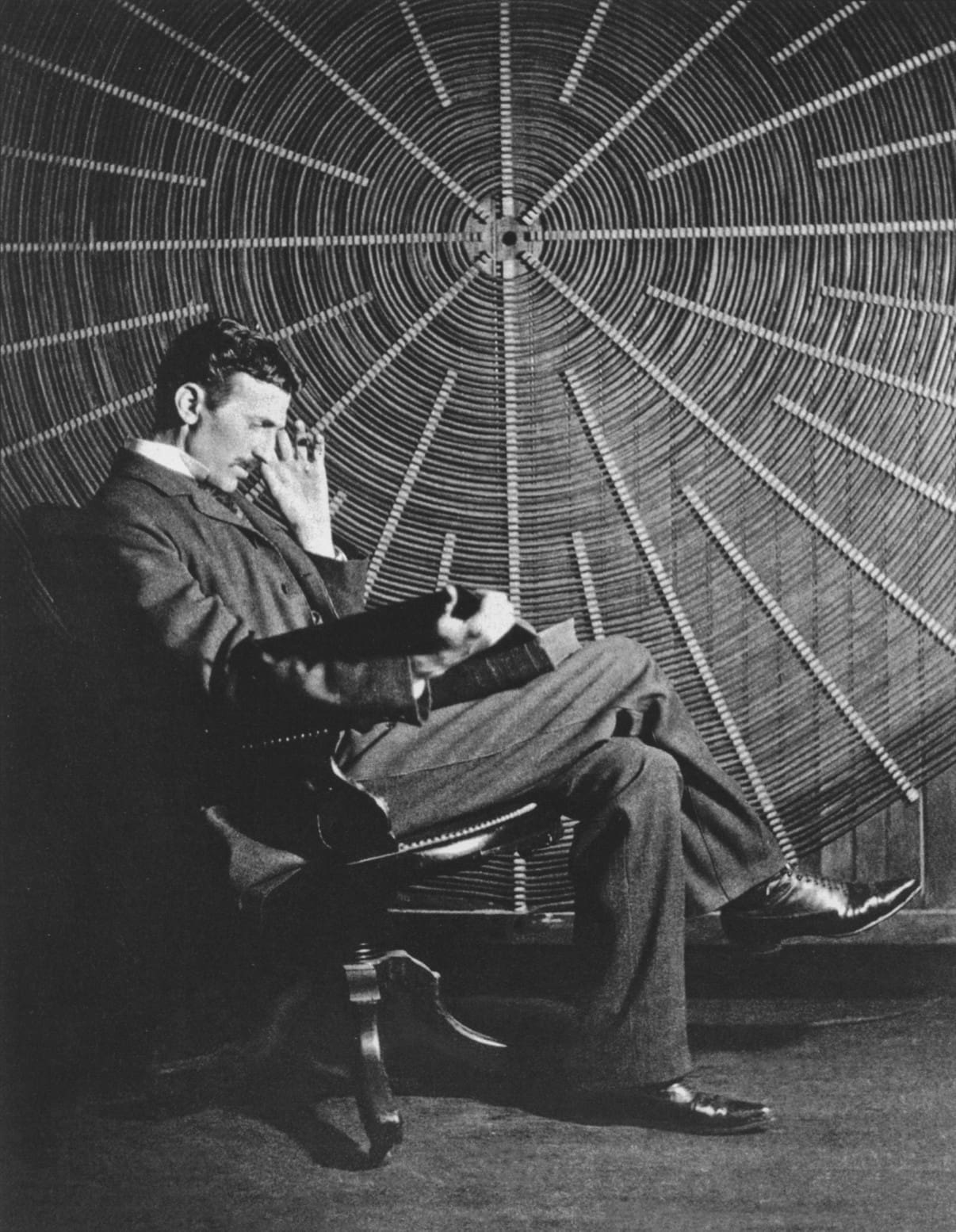 RIOT, NYC Creative Agency: Nikola Tesla sitting in a chair, reading a book, with a large spiral coil in the background, symbolizing his deep thoughts on electricity and the mysteries of the universe. Nikola Tesla sitting in a chair, reading a book, with a large spiral coil in the background, symbolizing his deep thoughts on electricity and the mysteries of the universe.