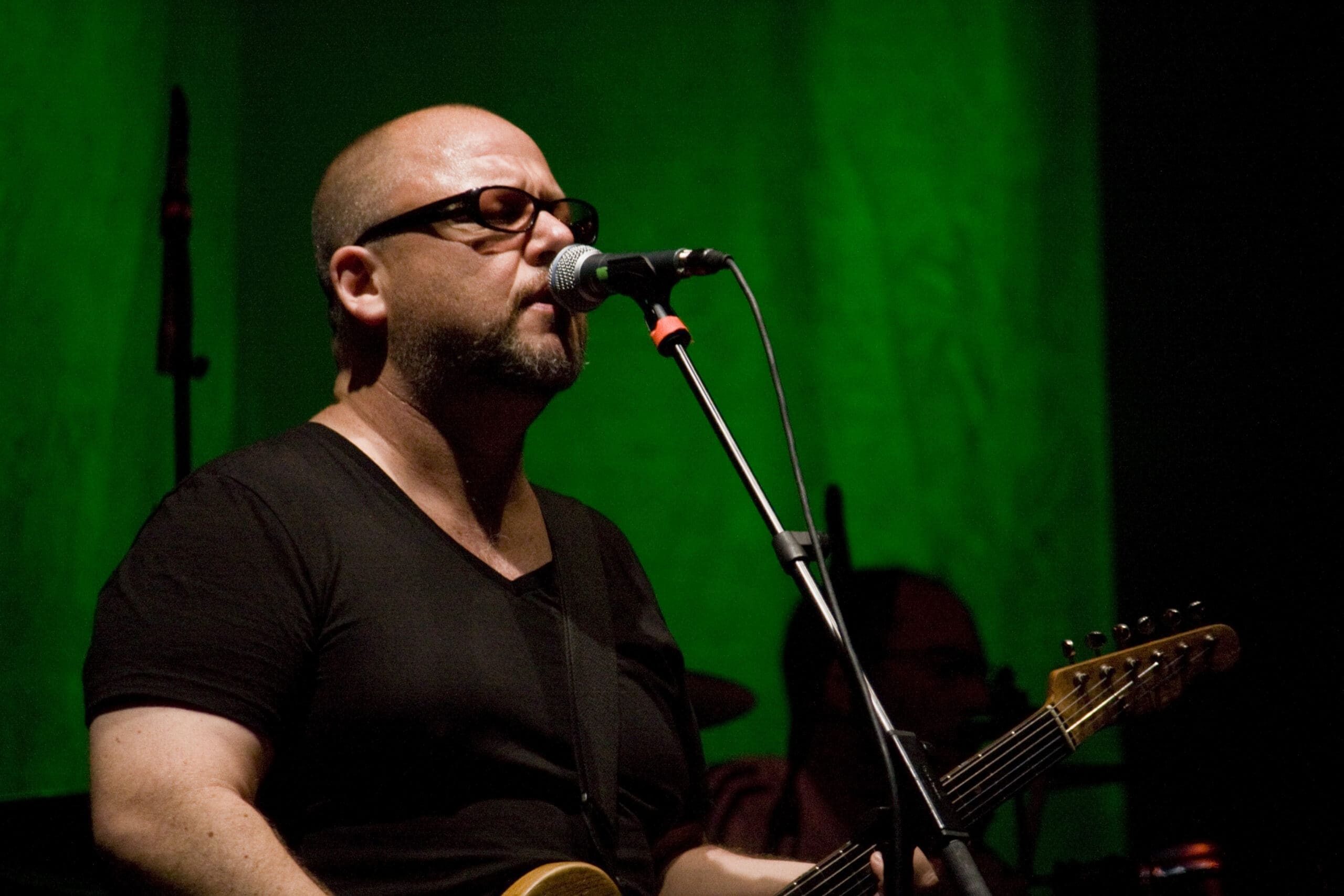 rank Black of the Pixies performing live, singing into a microphone while playing guitar.