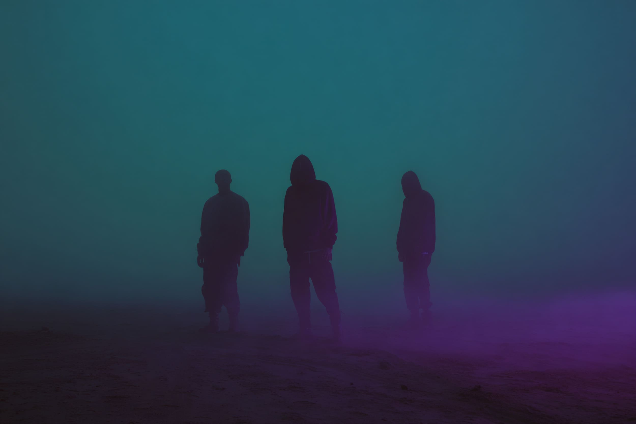 RIOT, NYC Creative Agency: Silhouetted figures standing in fog with teal and purple lighting, representing creative rebirth Silhouetted figures standing in fog with teal and purple lighting, representing creative rebirth