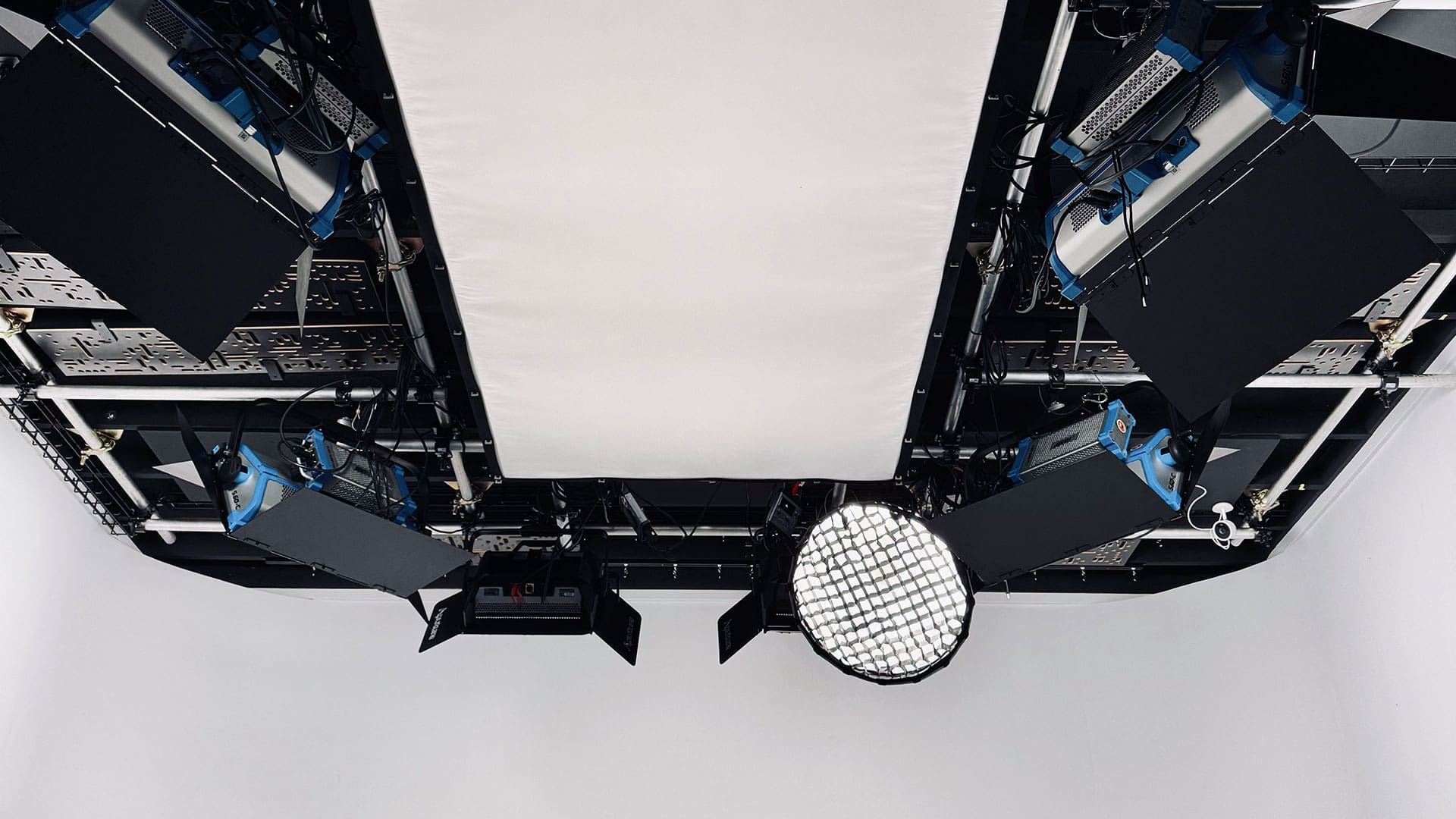 A detailed view of the lighting grid setup at RIOT studio, featuring multiple high-quality lights and equipment mounted on the ceiling for professional studio shoots.