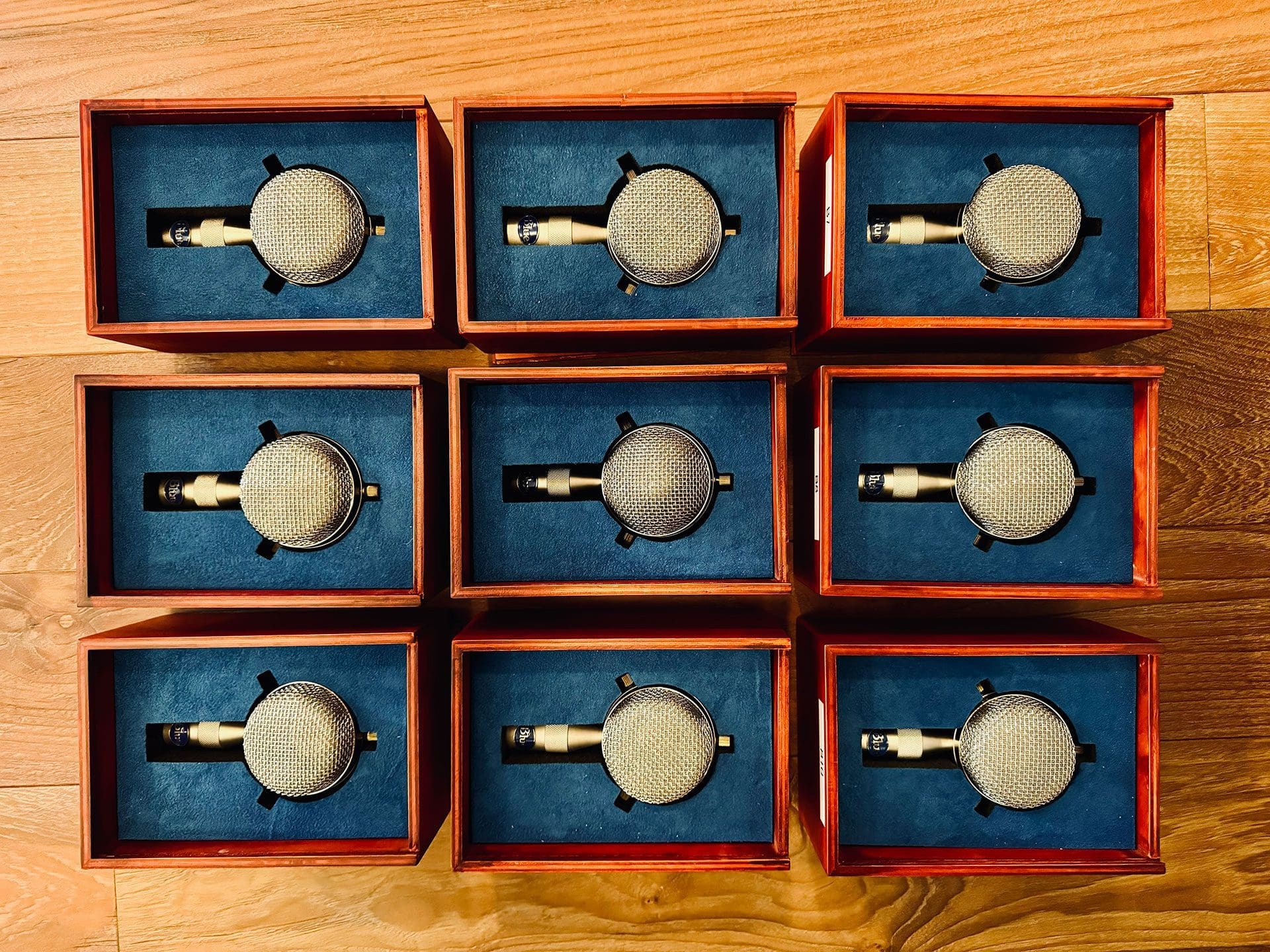 RIOT, NYC Creative Agency: Array of Blue Bottle microphone capsules in wooden boxes with blue velvet lining, displayed on a wooden surface Array of Blue Bottle microphone capsules in wooden boxes with blue velvet lining, displayed on a wooden surface
