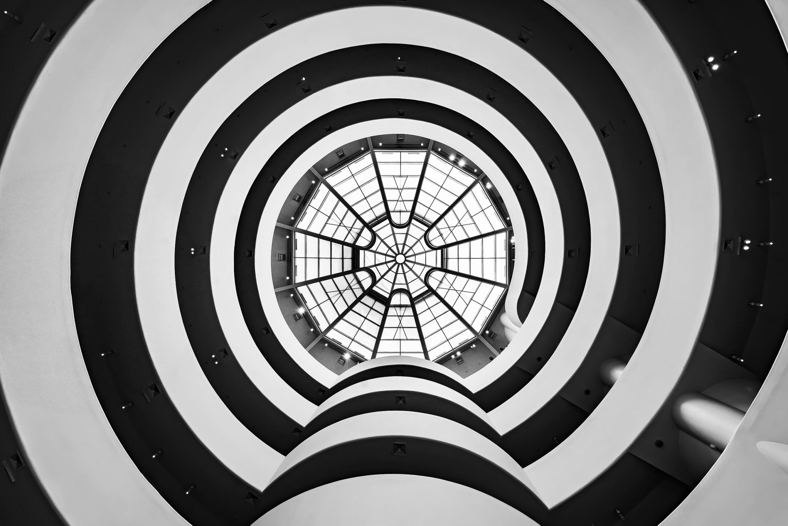 RIOT, NYC Creative Agency: The skylight of the Solomon R. Guggenheim Museum in New York, designed by Frank Lloyd Wright, featuring concentric circular designs viewed from below. The skylight of the Solomon R. Guggenheim Museum in New York, designed by Frank Lloyd Wright, featuring concentric circular designs viewed from below.