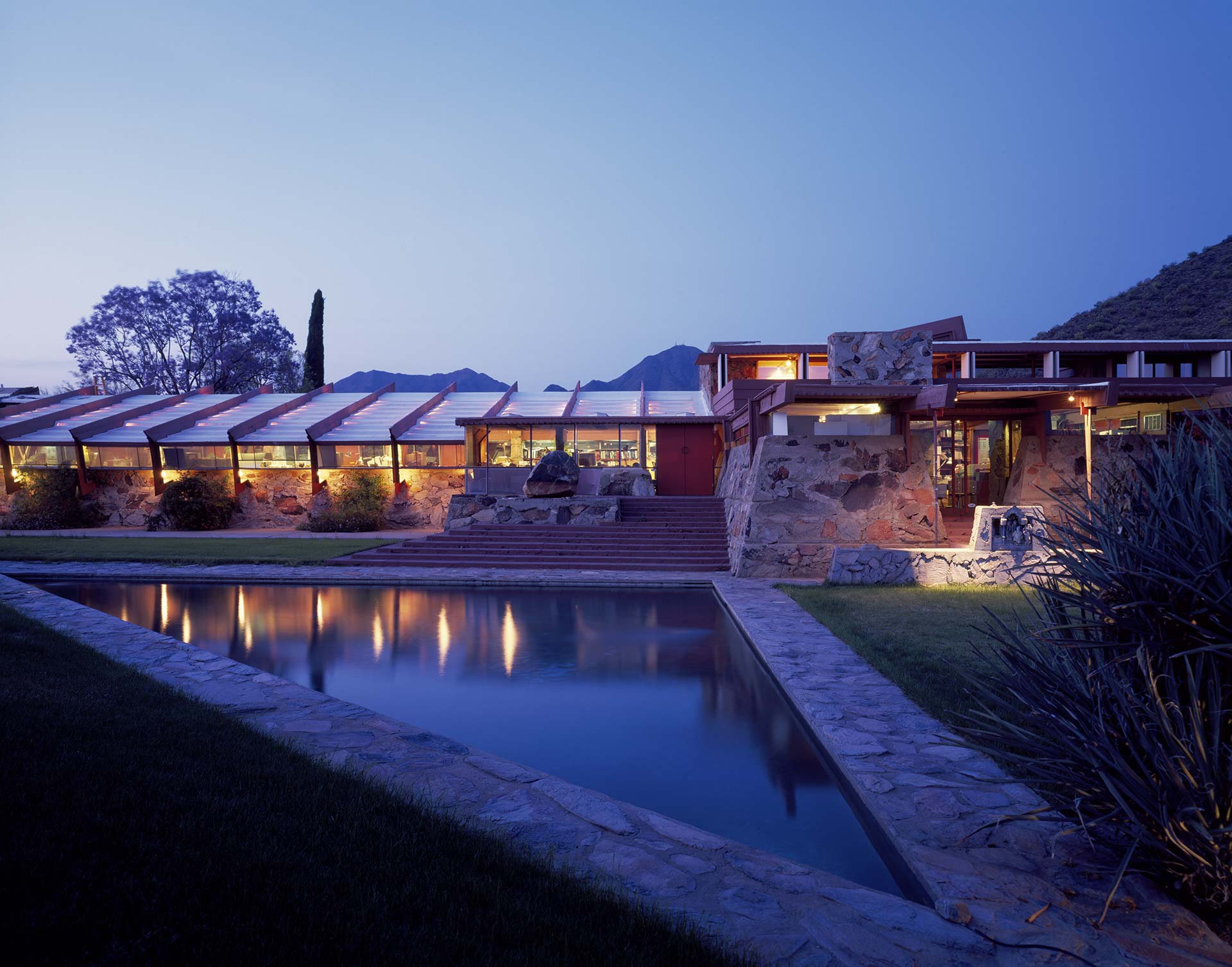 Taliesin West, Frank Lloyd Wright’s desert home and studio, located in Scottsdale, Arizona, illuminated at dusk with the mountains in the background.