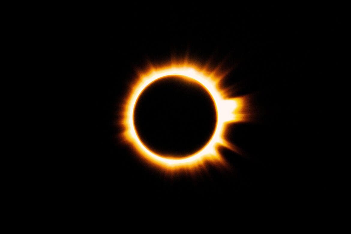 Solar eclipse with a bright orange ring of fire glowing against a black sky in Bleed Electric’s This Is My Masterpiece visuals