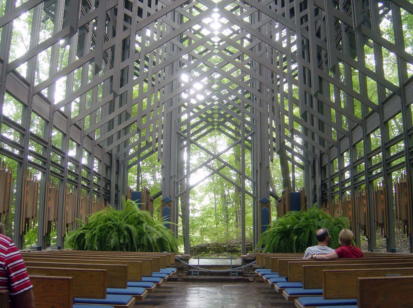 Interior view of Thorncrown Chapel, designed by E. Fay Jones, featuring a glass and wooden lattice structure that blends with the surrounding forest.